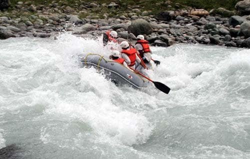 People rafting through strong white water rapids in a rocky river