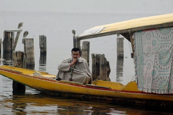 Man enjoying hookha in a boat during Srinagar In winter