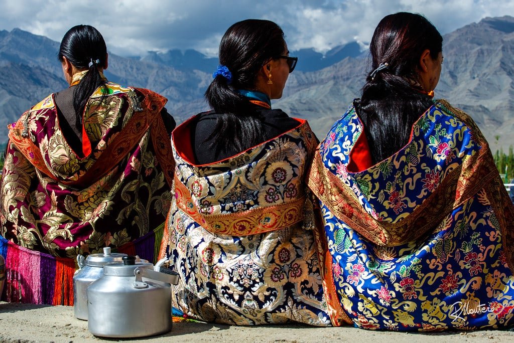 Women posing for a photo in colorful Ladakhi attire with mountains in the background