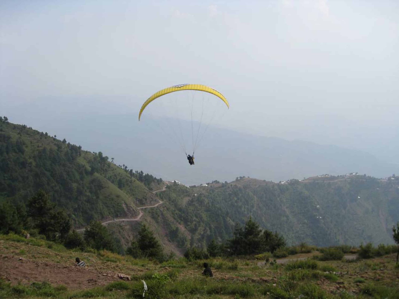 Person paragliding over green hills and valleys in srinagar