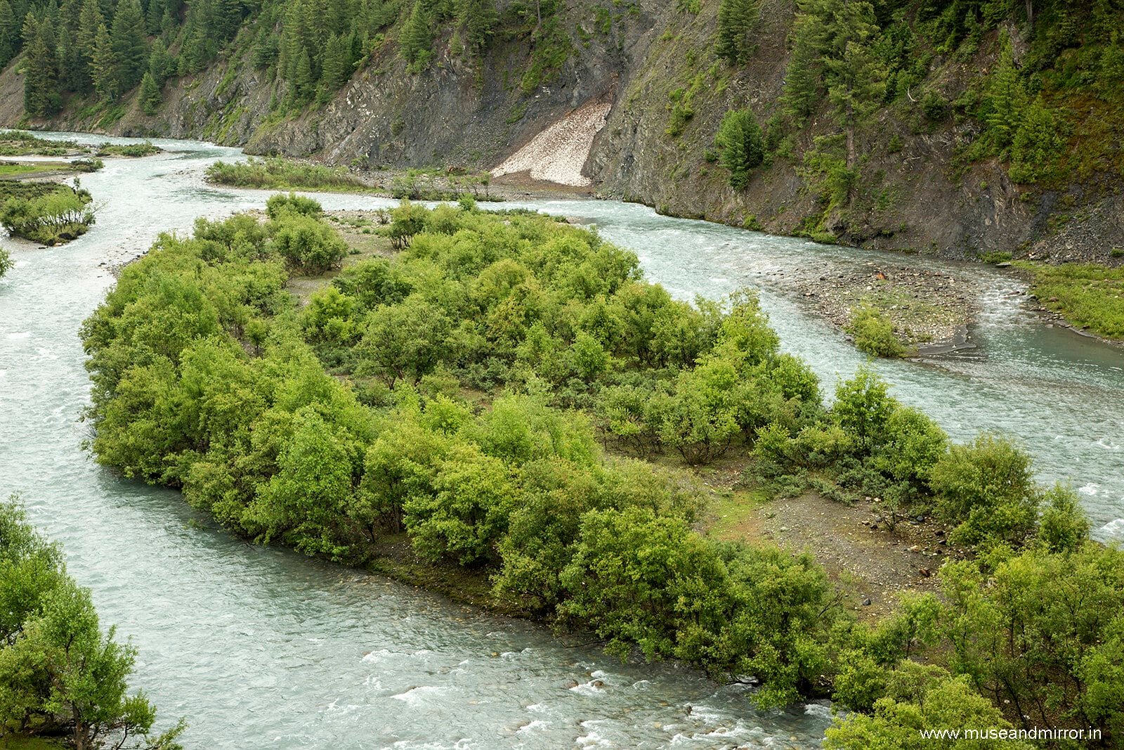Lush green island in the middle of a winding lidder river surrounded by forested hills at tulail valley