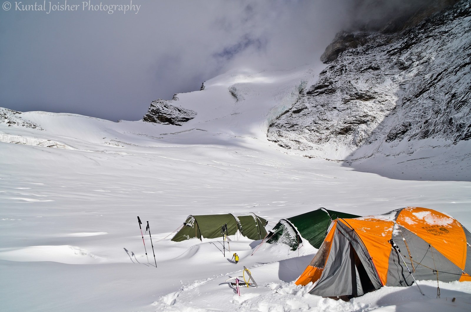 Snowy mountain campsite with colorful tents and trekking gear under cloudy skies in pahalgam, kashmir
