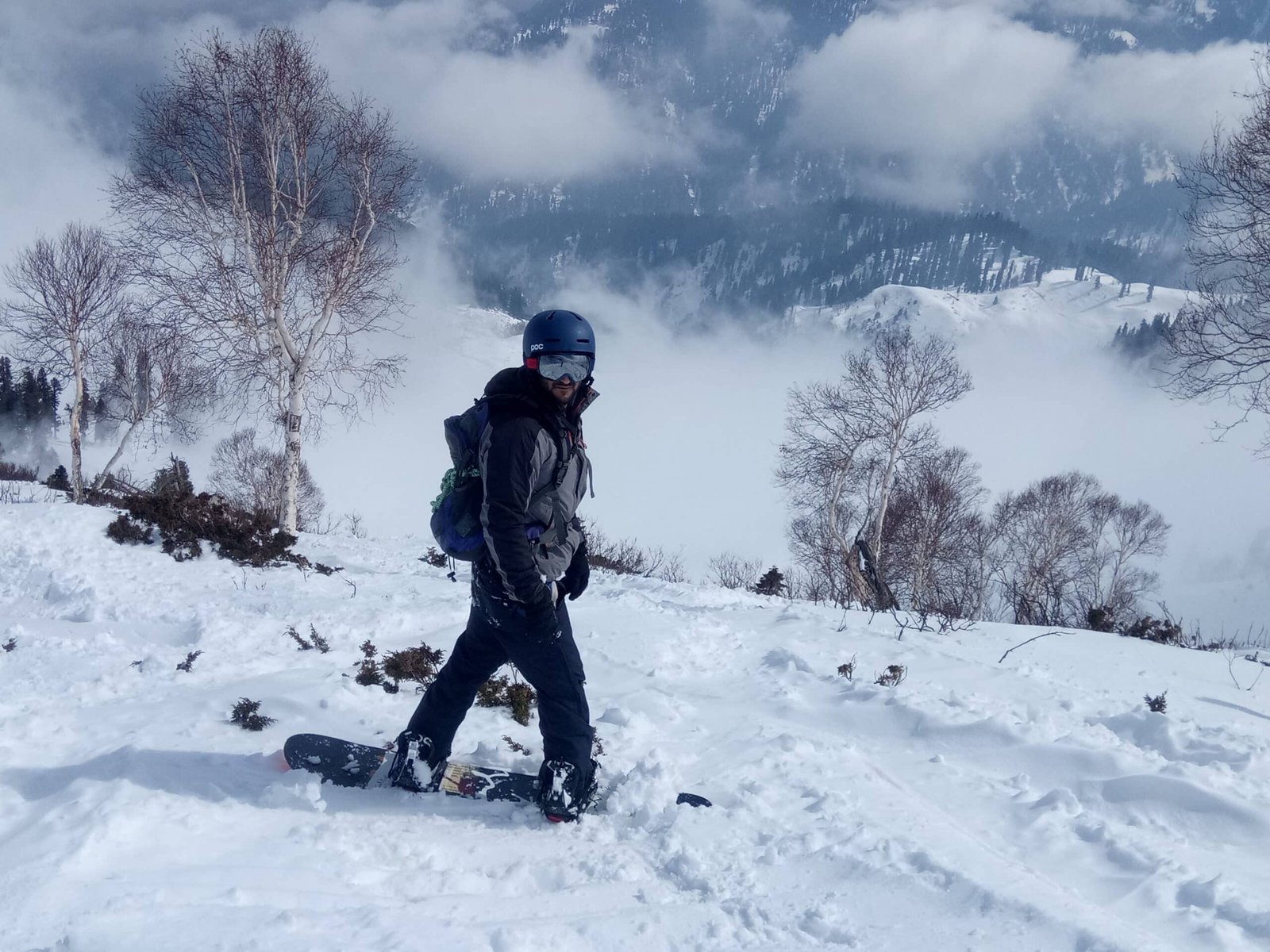 Snowboarder standing on a snowy slope with misty mountains in the background
