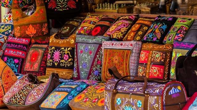 Colorful embroidered Kashmiri bags and cushions displayed at a market stall