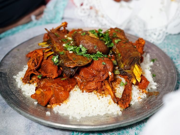 Traditional Kashmiri Wazwan dish served on a metal plate with rice and various cuts of spiced meat garnished with fresh coriander