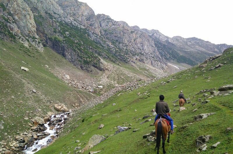 Tourists are riding horses and the horses are climbing the hills in pahalgam