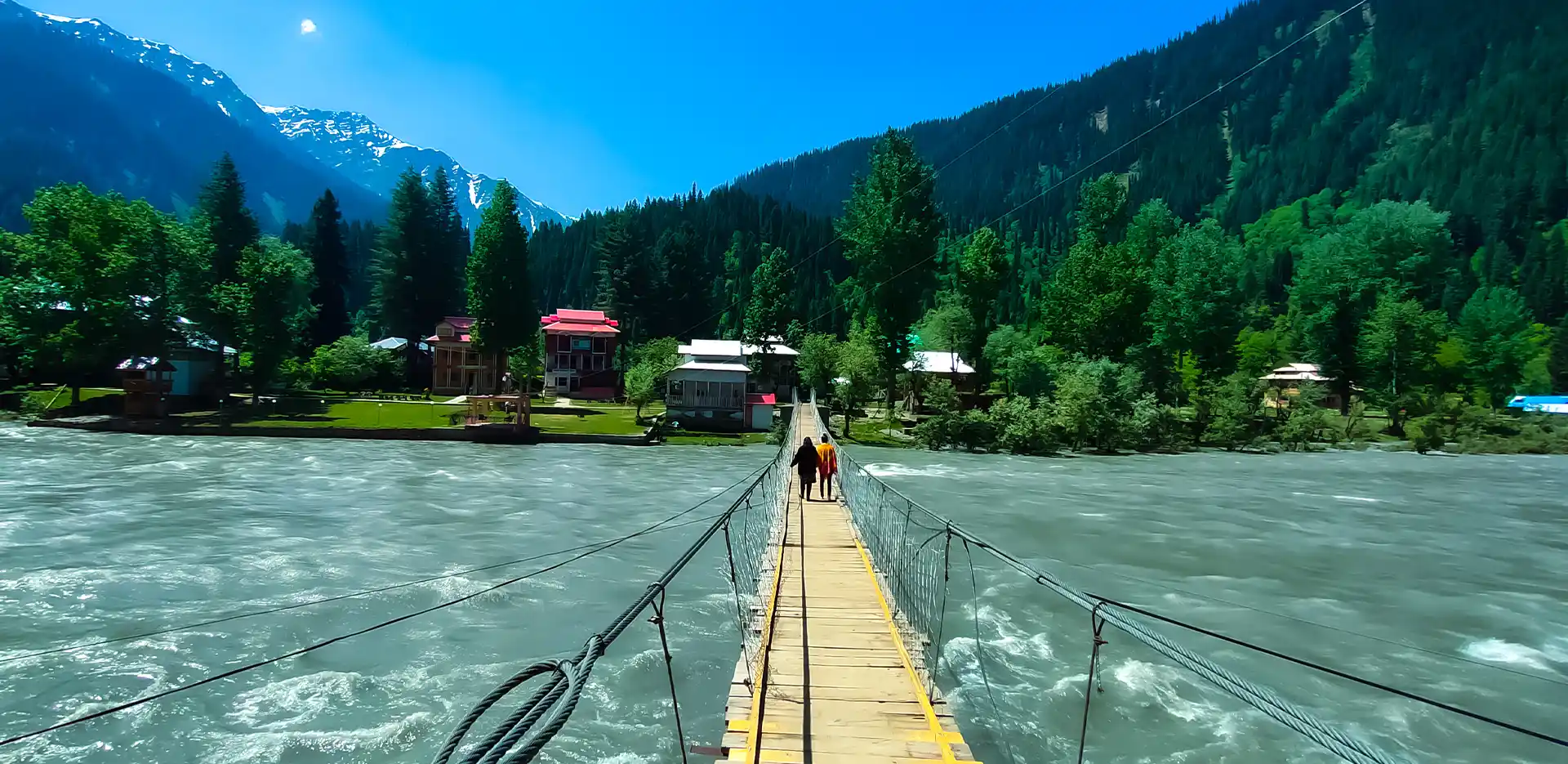 People walking on a hanging bridge over a river in a gurez village