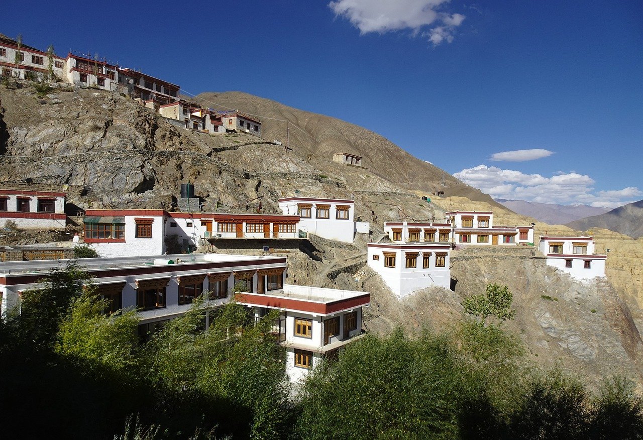 White monastery buildings on a rocky hillside under a clear blue sky
