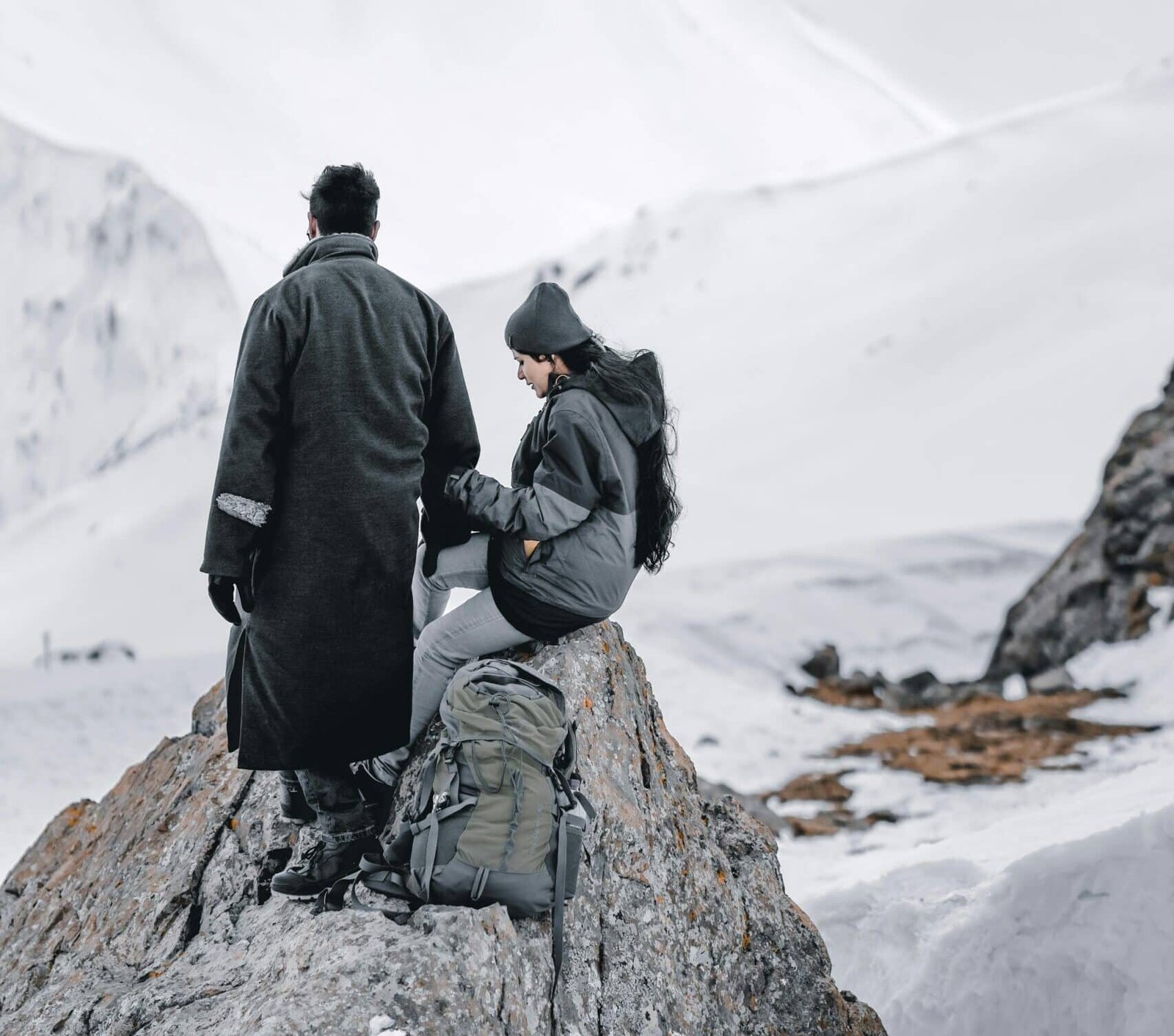 Couple sitting on a snowy mountain rock