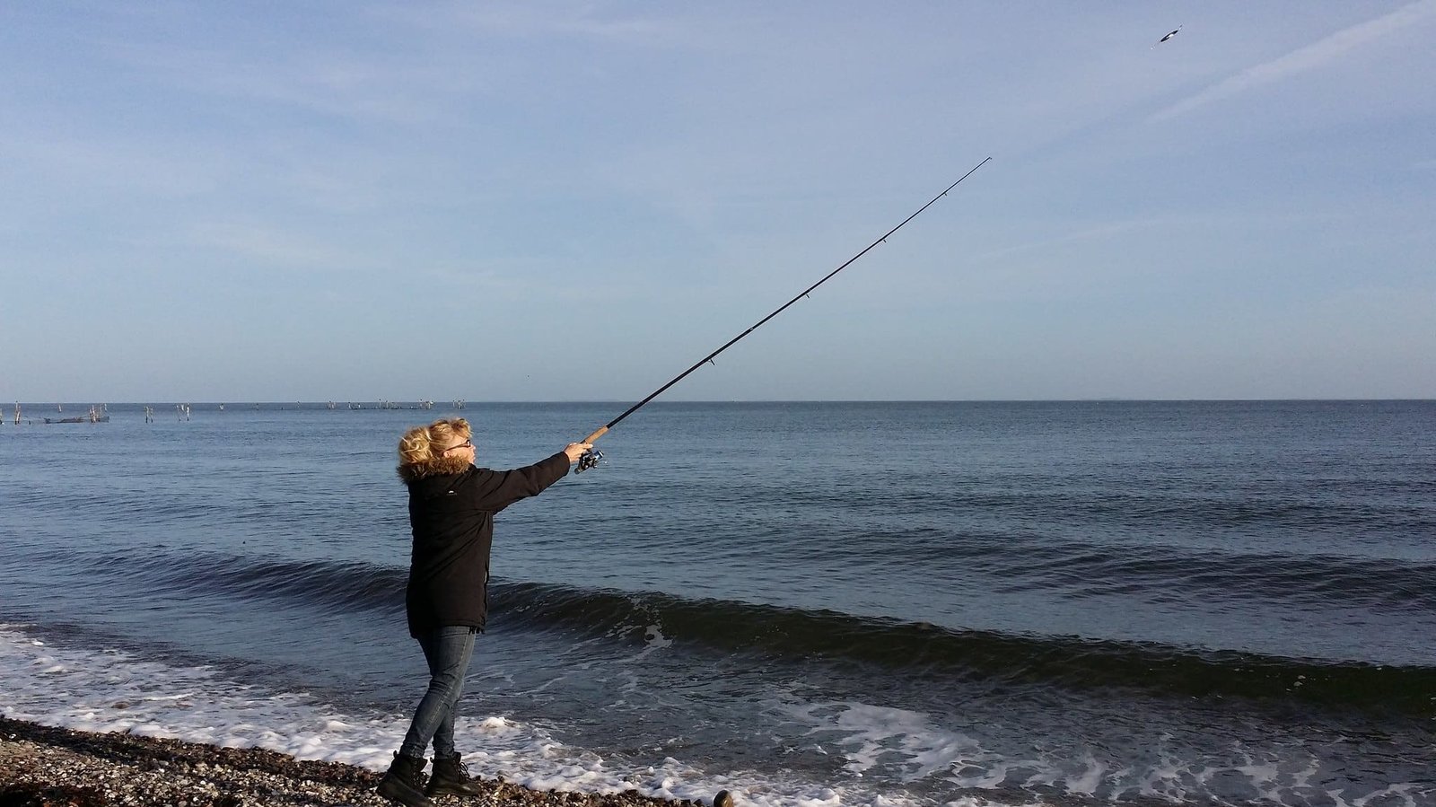 Person fishing from a rocky beach