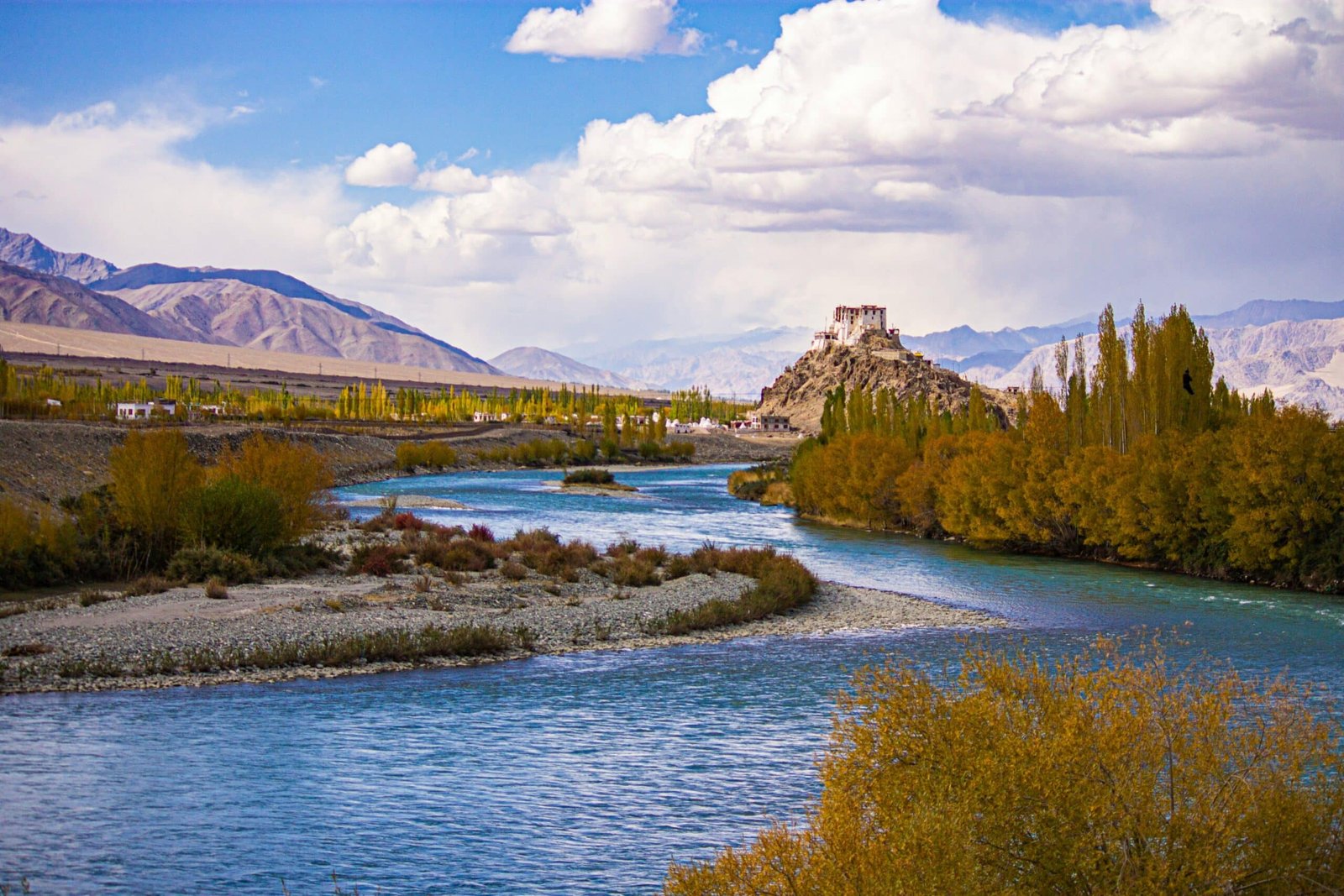 River flowing through a valley with a monastery on a hill.