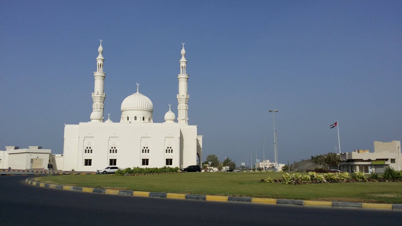 White mosque with domes under a clear blue sky