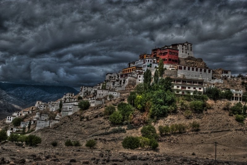 Takthok Monastery on a rocky hill under dark cloudy sky