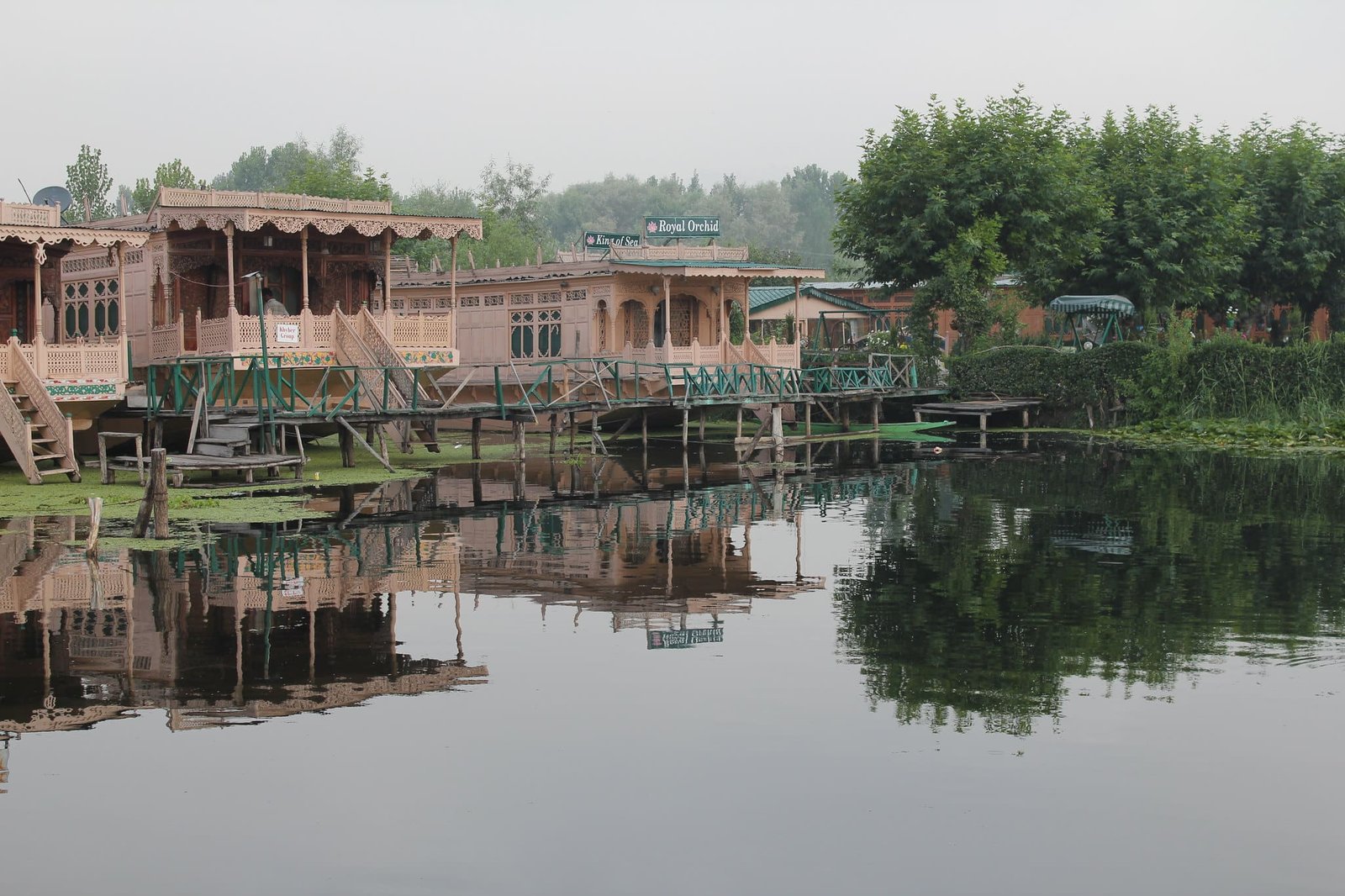 Traditional wooden houseboats on a calm lake with lush greenery.