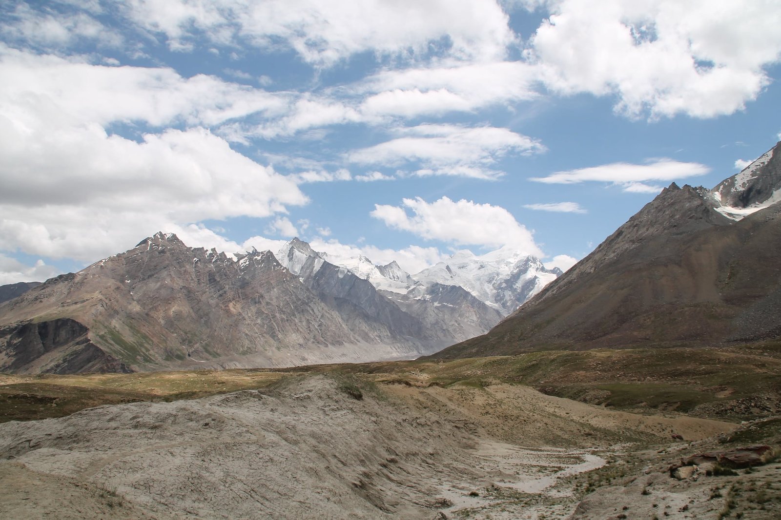 A scenic view of Pensi La Pass showcasing rugged brown hills in the foreground
