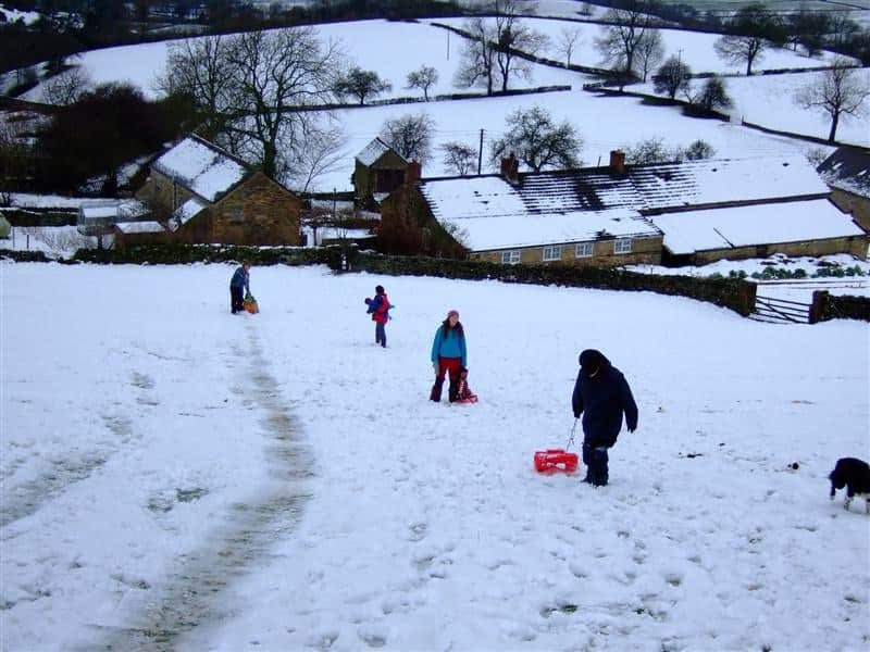 People sledging on a snowy hill near houses in kashmir