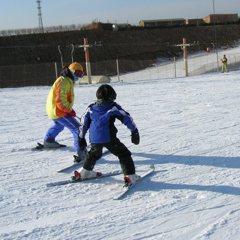 Ski instructor teaching a child to ski on a snowy slope