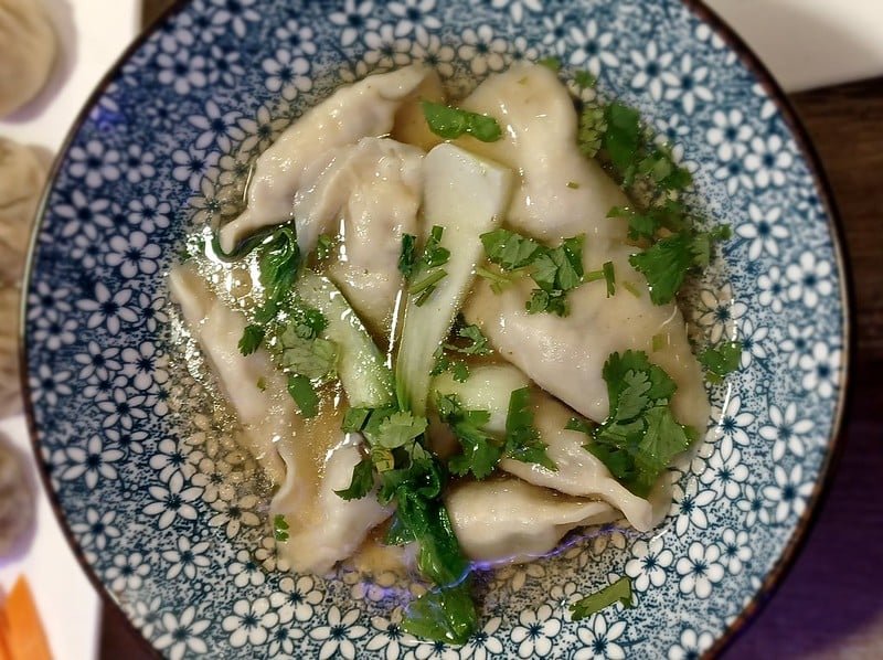 Bowl of Mokthuk dumpling soup garnished with fresh herbs