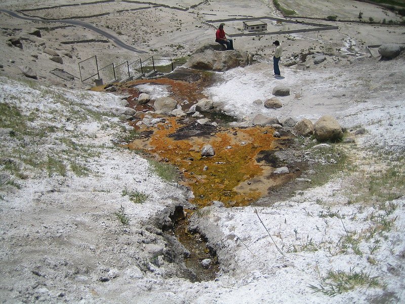 People near a stream of hot spring water flowing through a rock in nubra valley