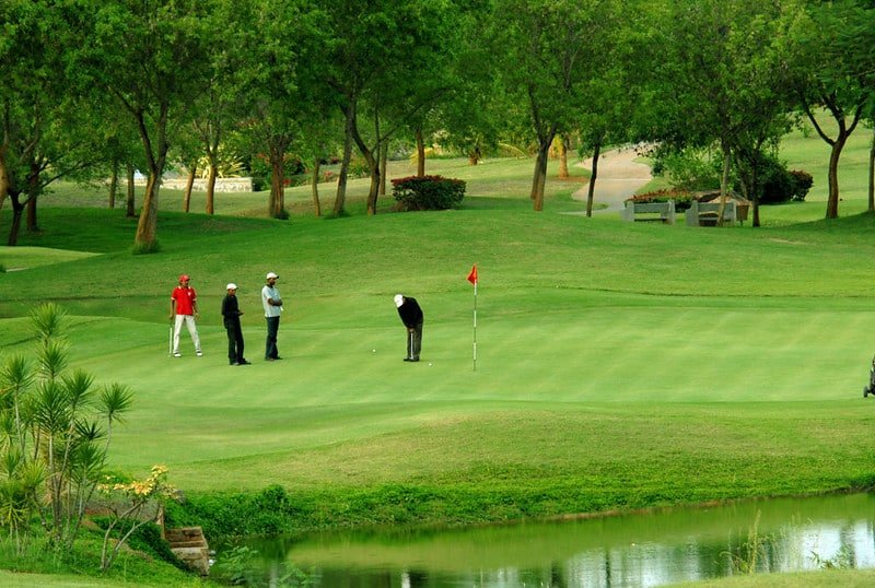 People playing golf on a green course surrounded by trees in Gulmarg.