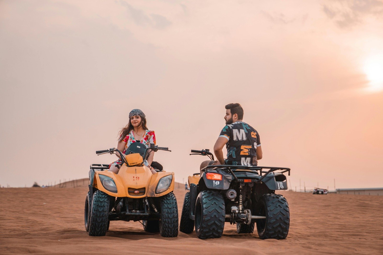 Two people riding quad bikes on sand dunes at sunset in ladakh