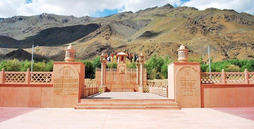 Drass War Memorial with mountain backdrop and regimental flags