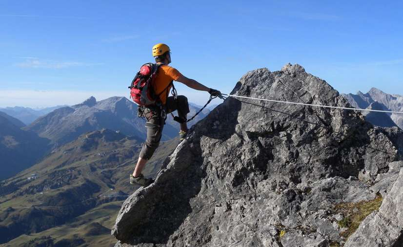 Climber scaling rocky mountain with safety gear in Patnitop