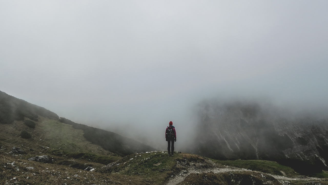 A trekker standing on a foggy mountain ridge with mist covering the view at Patnitop