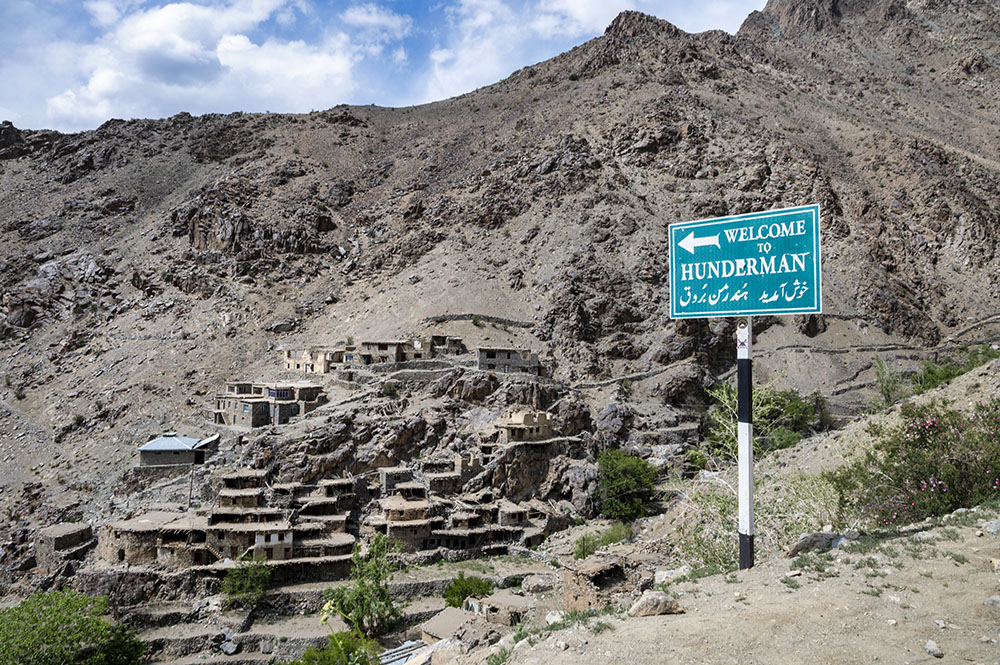 Stone houses of Old Hunderman village built on a rocky hillside with welcome sign