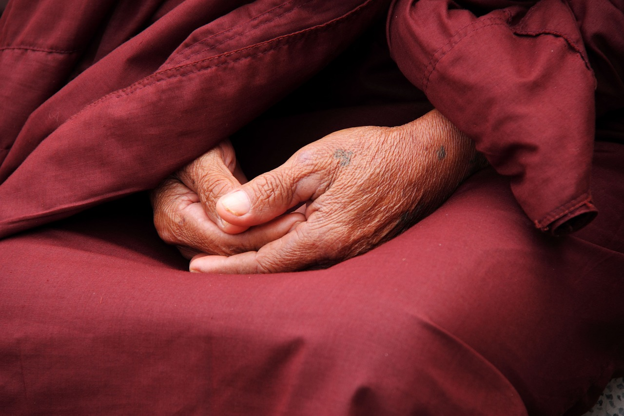 Close-up of a Buddhist monk’s hands resting in meditation