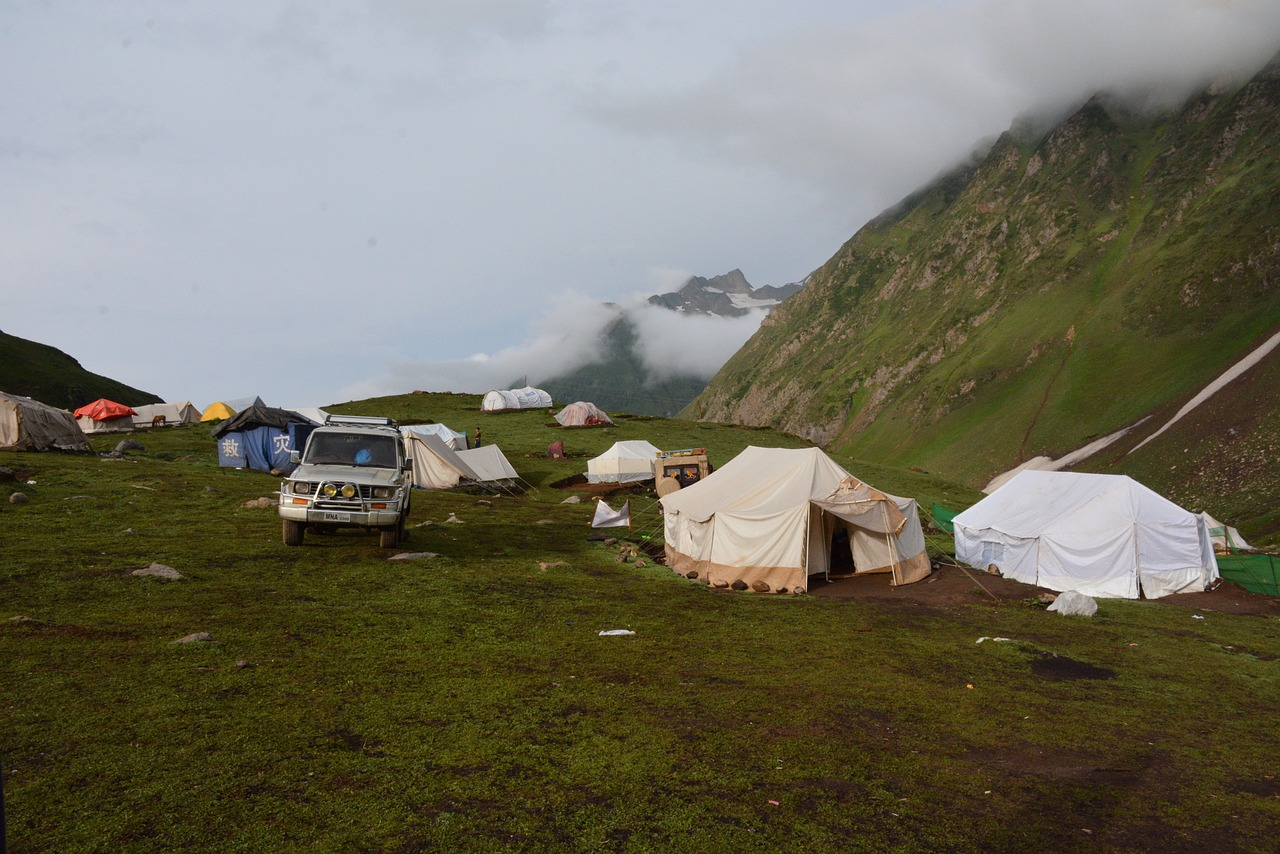 Mountain campsite with tents, SUV, and misty peaks in Patnitop, Kashmir