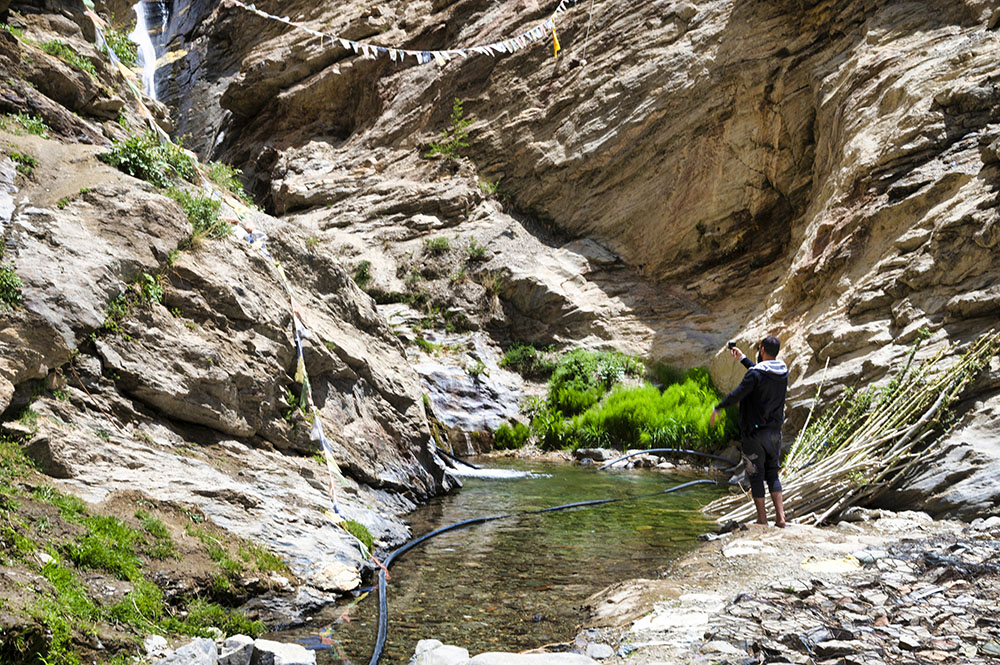 Man standing near a rocky waterfall in Sheela Village