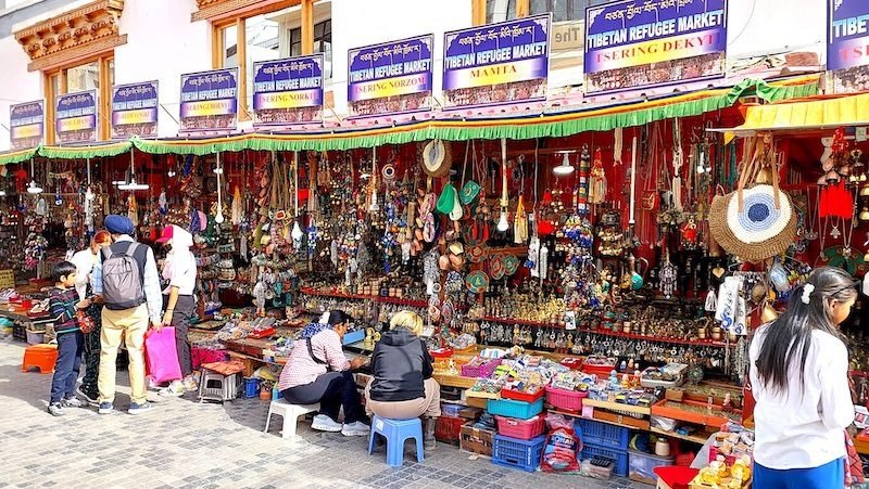 Colorful Tibetan market stalls with souvenirs and people shopping in Leh