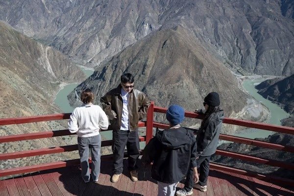 Family enjoying mountain and river view from a wooden viewpoint in Leh-Ladakh