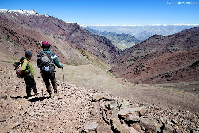 Trekkers walking along a rocky trail with colorful mountains in Ladakh